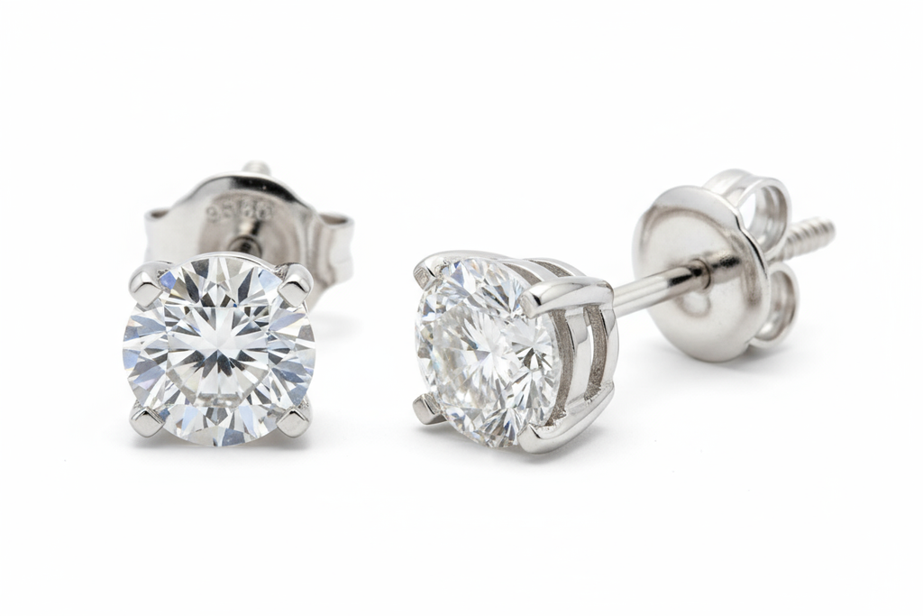 Diamond solitaire earrings with 4 prongs and a screw on backing in white gold, close up showing fine craftsmanship 